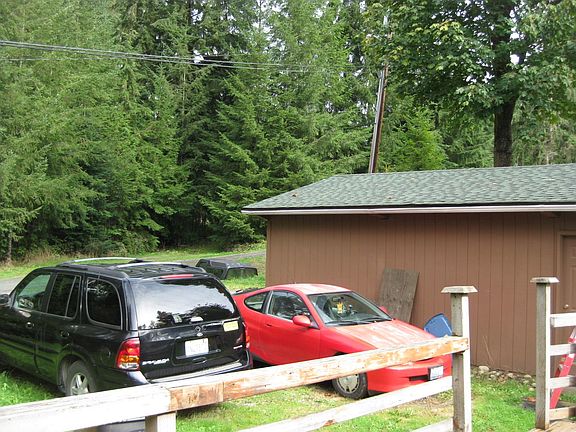 Current tenants' cars parked next to garage and on north side of house. Front deck railing.