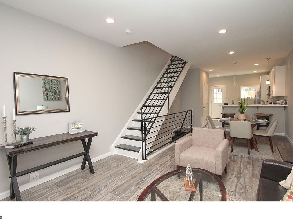 First floor open-concept living room and dining room, leading to the kitchen. Doorway to the half-bathroom is visible past the basement entryway on the left