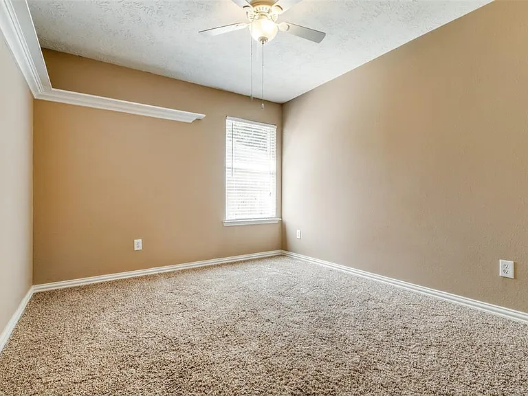 Second bedroom has built-in shelf, ceiling fan, comfortable carpet, window and clothes closet.