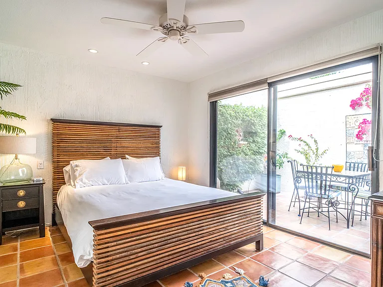 Guest bedroom with queen bed, crisp hotel-quality linens, and sliding doors opening to the private courtyard patio. Bright, airy, and thoughtfully designed for comfort and extended stays.