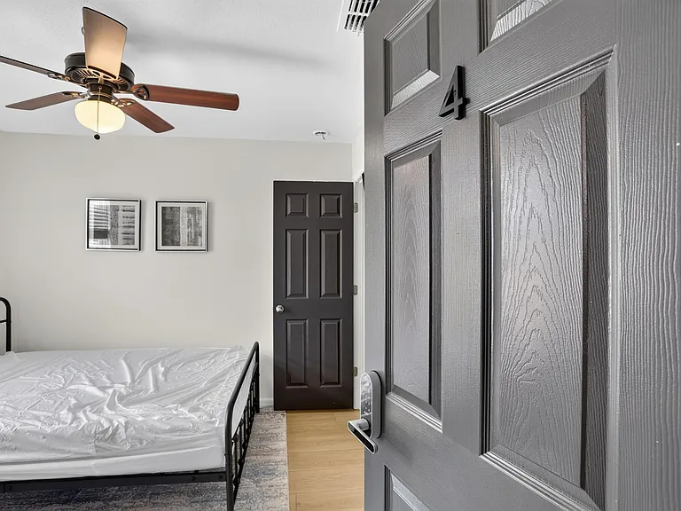 Private bedroom featuring a ceiling fan with light, neutral walls, and space for a full bed and essentials.