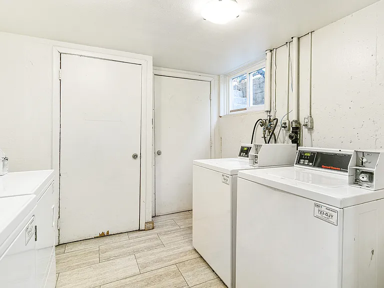 Bright and efficient laundry room with two modern washing machines and stylish light wood flooring.