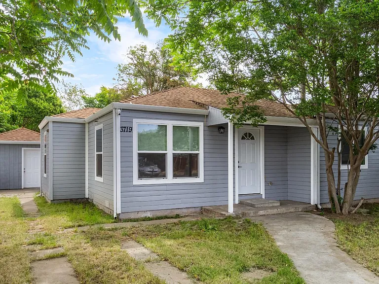 Single-story home with covered front entry, large front windows, and a detached storage/garage building off the driveway.