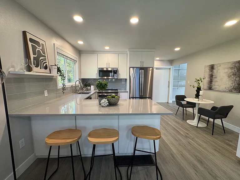 Contemporary kitchen with quartz countertops, stainless steel appliances, and sleek cabinetry & an eating bar.
