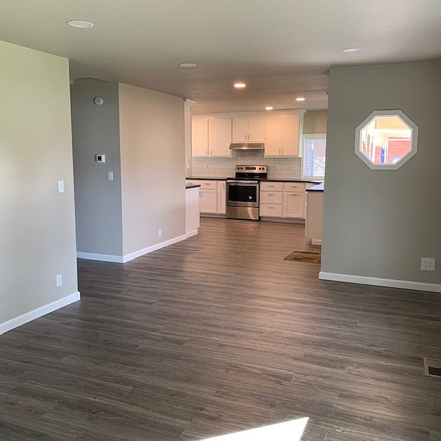 Beautiful open living room, dining area, and kitchen with hallway leading to bedrooms and first bathroom.