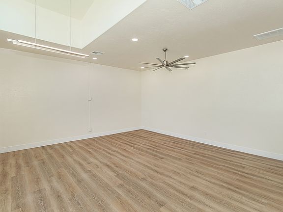 Large High Vaulted Ceiling with Custom Fan, Amazing Large Windows, Luxury Vinyl Plank Flooring, And Automatic Roll Down Shades.