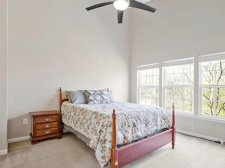 Spacious, light-filled, and lined with oversized picture windows, the primary bedroom feels like a quiet retreat above the trees.