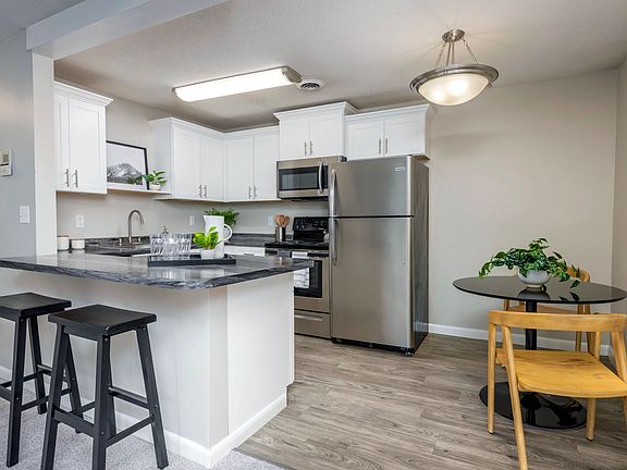 Discover kitchen elegance at Welby Park Estates, where the open concept living seamlessly connects with a welcoming dining area graced by an inviting light fixture, and an elegant breakfast bar for extra seating.