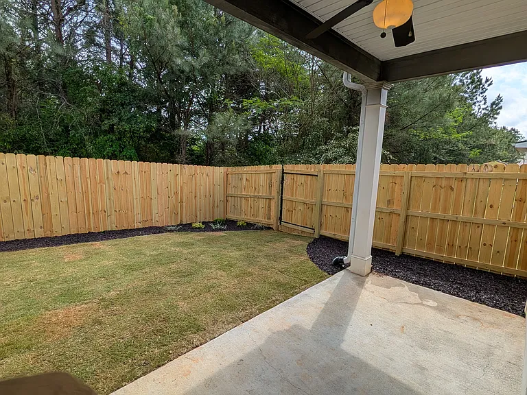 Fenced back yard with two gates, covered patio, ceiling fan