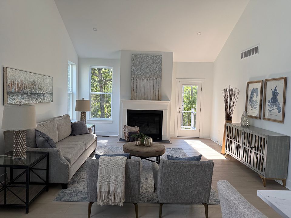 striking centerpiece of the home, featuring soaring two-story ceilings and expansive windows that flood the space with natural light. Designed with an open-concept layout, it flows seamlessly into the gourmet kitchen and dining area.