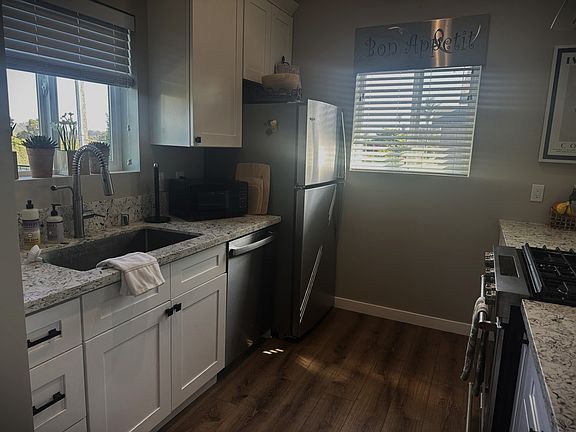 Kitchen equipped with deep sink, stainless steel dishwasher, refrigerator, high end range with stainless steel range hood.