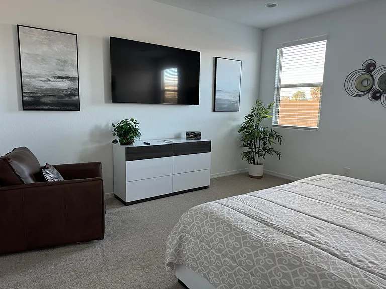 Primary Bedroom with view of 65" smart tv, a comfy chair for reading etc. and general view of the room