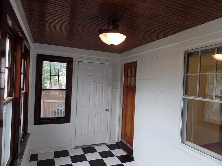 Three Season Porch. Window goes to Back Bedroom. Wooden door goes to Kitchen. White door goes to Deck.
