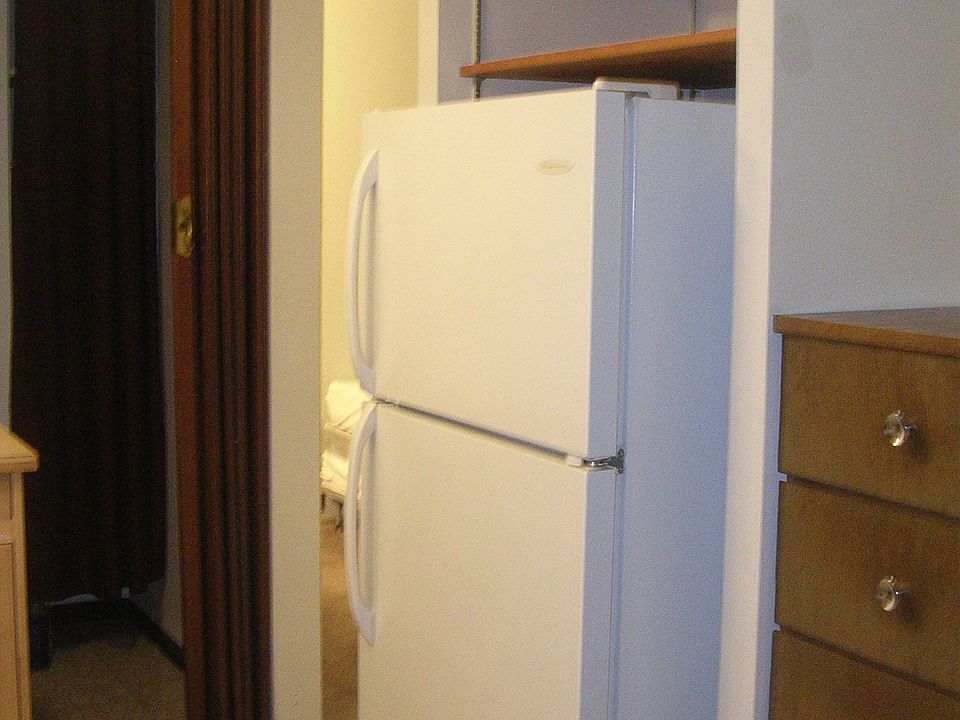 Built in linen chest sits next to fridge, which has storage shelves above for easy storage of kitchen items.