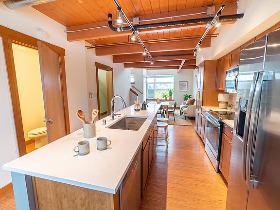 Kitchen with large prep island, stainless steel appliances, and exposed wood beams at Union Bay Lofts in Seattle.