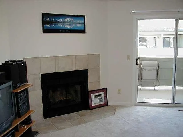 Living room with a real fireplace and lots of natural light from the sliding glass doors opening to the private balcony