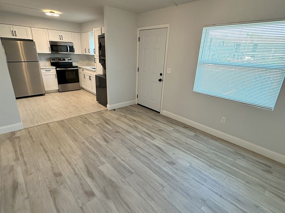 A view of the living and dining room extends into the updated modern kitchen, where large windows allow gorgeous natural light to flood the space.