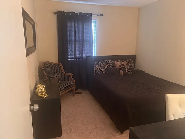 Second bedroom includes queen size bed with storage drawers underneath, desk, dresser, and chair.