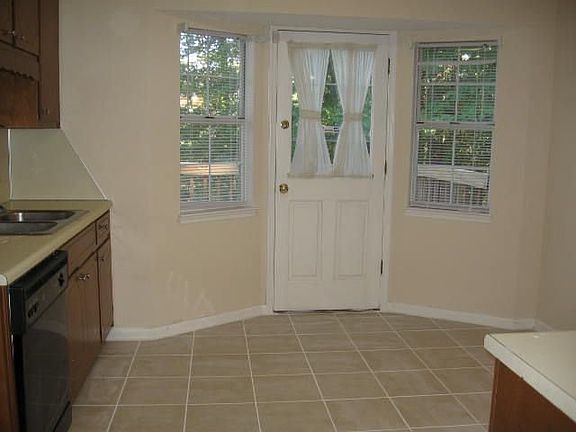 Kitchen with new tile flooring, new stove, bayed windows and door to back deck