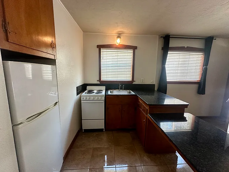 Kitchen with updated appliances, refrigerator built in for more space, granite counter tops and new tile flooring.