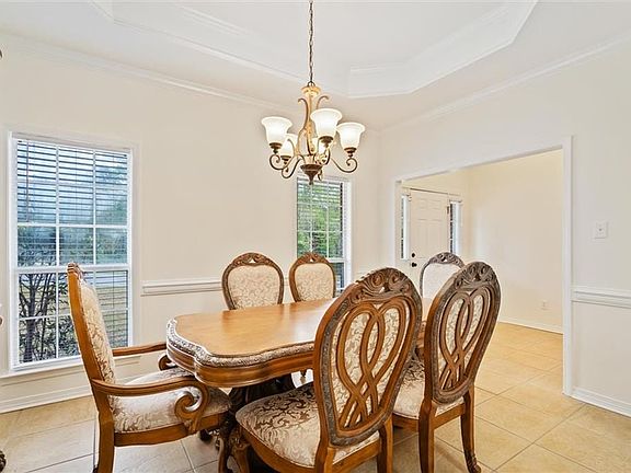Dining space featuring a chandelier, a raised ceiling, light tile patterned floors, and crown molding