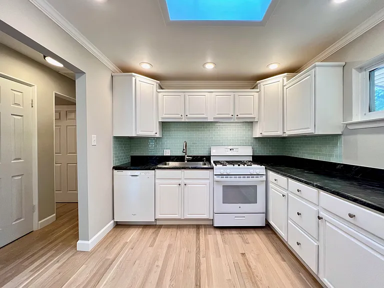 Custom cabinets, dishwasher, gooseneck sink with sprayer, garbaghe disposal, gas range, plenty of counter space and skylight. Full-sized pantry in hallway.