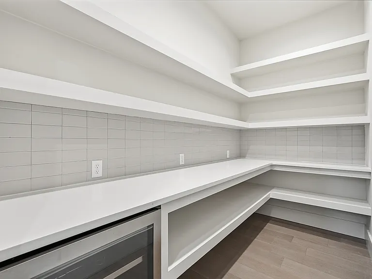 Spacious walk-in pantry with custom shelving, ample storage, and convenient prep space.