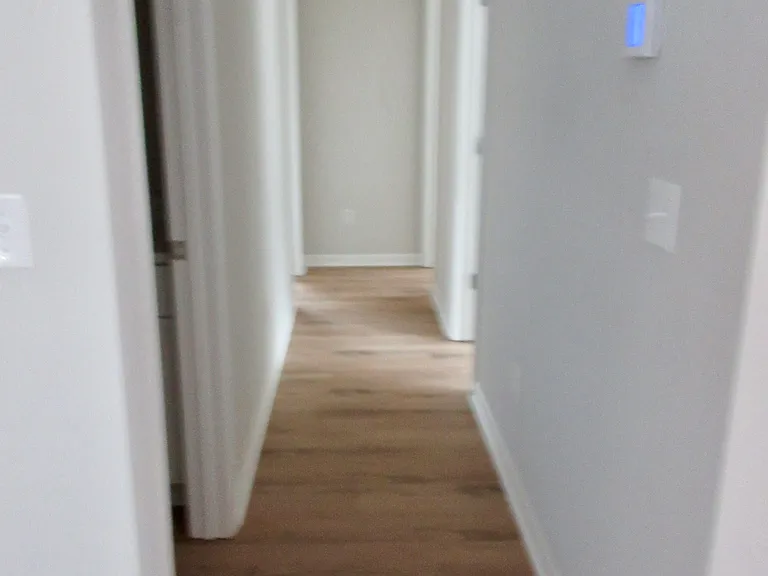 Hall across from kitchen leading to bedrooms & bathrooms, access to attic with pull down steps
