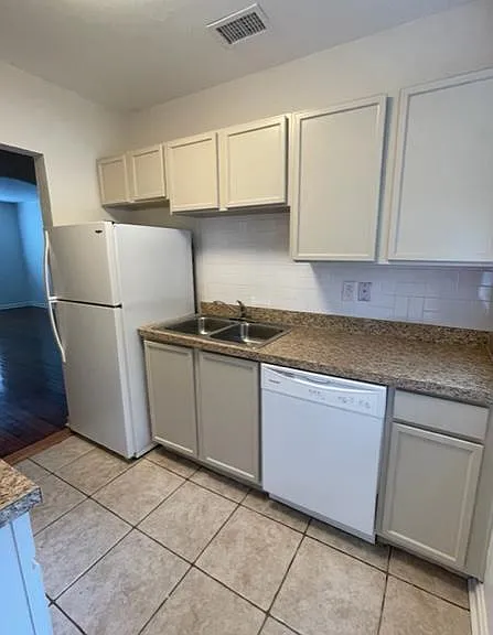 Kitchen with new paint on cabinets, refrigerator and dishwasher.