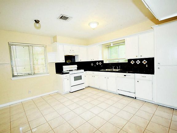 Kitchen has tile floor & large cabinets.