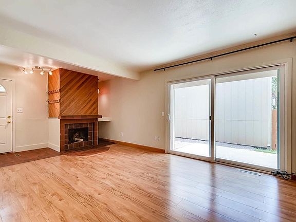 Main level living room with gas fireplace and slider leading to side patio and newish flooring.