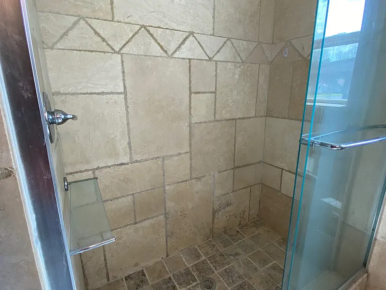 Large tiled walk in shower with sliding glass doors.