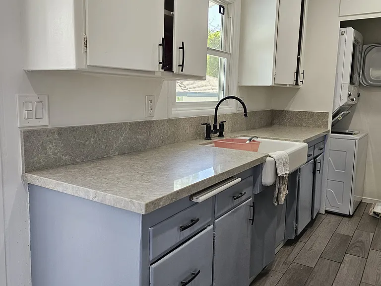 Kitchen sink, countertop, upper and lower cabinets. Laundry closet is next to kitchen, with washer and dryer.