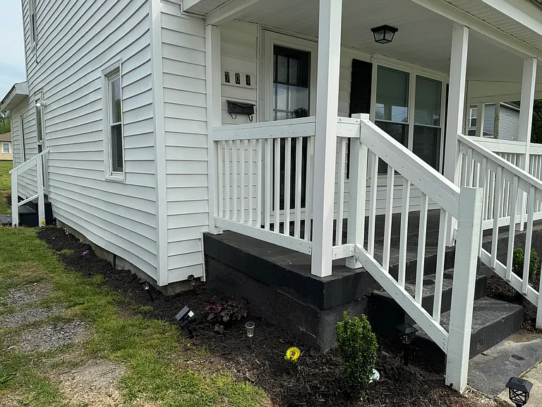beautiful landscaping and entry staircase leading into the the front of house
