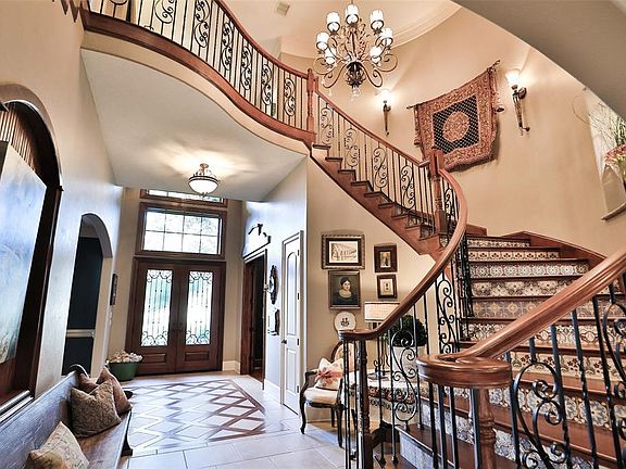 Beautiful curved staircase featuring two hundred year old French encaustic tile in a custom layout designed for this home. Looking towards the front entry doors from the living room of the home.