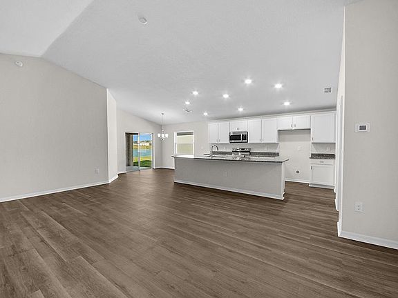 Inside, you ll find a spacious, open living area with luxury vinyl plank flooring, under an airy vol