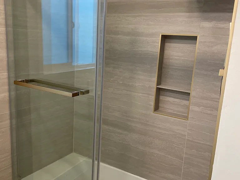 Bathroom 1 - custom-designed vanities, Delta gold hardware, large-format tile, and modern rainfall showers