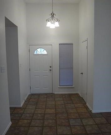 Vaulted ceiling in entry with recent light fixture, recent paint, tile floor and walk in closet opens to living room.