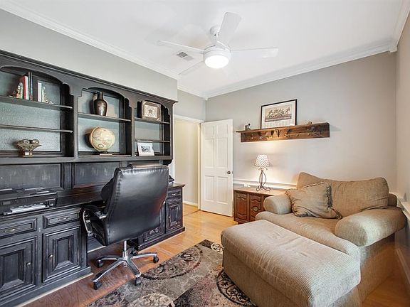 Study off foyer features wood floors, built-in desk, crown molding, a ceiling fan and plantation shutters