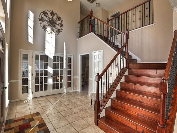 Entry with high ceilings,tile wood stairs and wrought iron spindles.