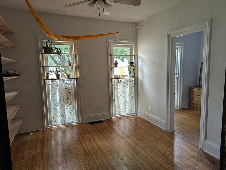 Second living room- has been used as a dining room, or as a bedroom with smaller bedroom as an office. Wall to wall shelving to the left. Front bedroom to the right. Photo taken from the french doors in the living room