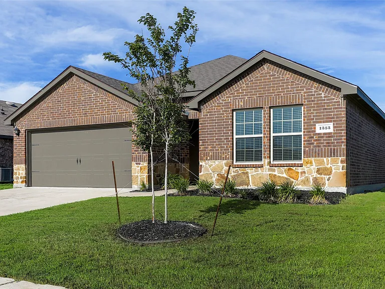 Brick exterior with stone accents, featuring a two-car garage with a panel door, dual pane windows with blinds, and a landscaped front yard