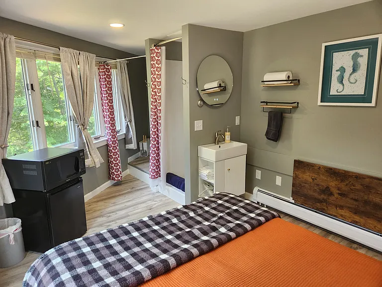 Bedroom 3 with queen bed on second floor, separate entrance, mini-fridge, mircowave, smart TV, fold away table and chairs, shower stall, bathroom sink, toilet, and views of backyard.