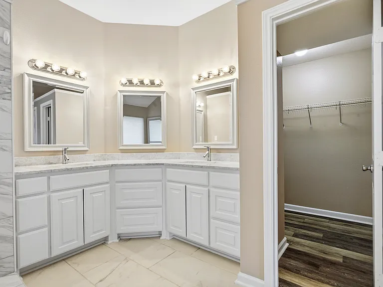 Primary bathroom with dual vanities and walk-in closet