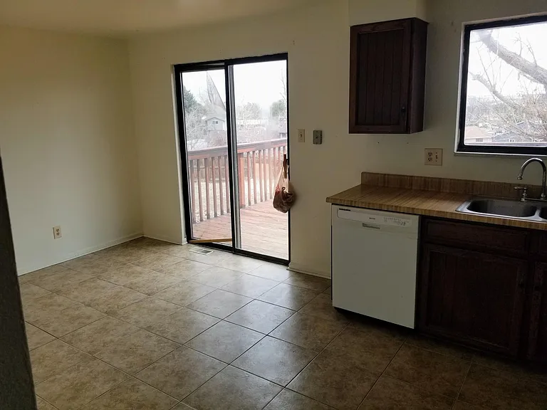 Eating area in large kitchen w/ sliding door out to patio and door out to garage.