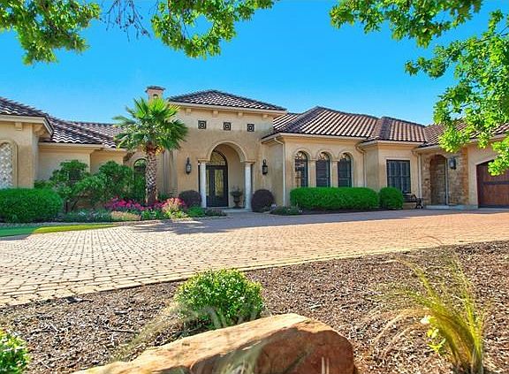Tile roof adorns this 1-Story home with 4-car garage with beautiful wood doors