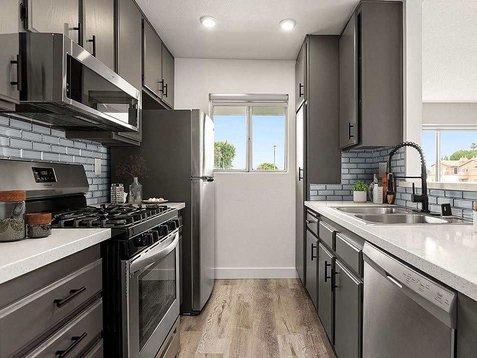 Tiled kitchen with stainless steel microwave, oven, and fridge.