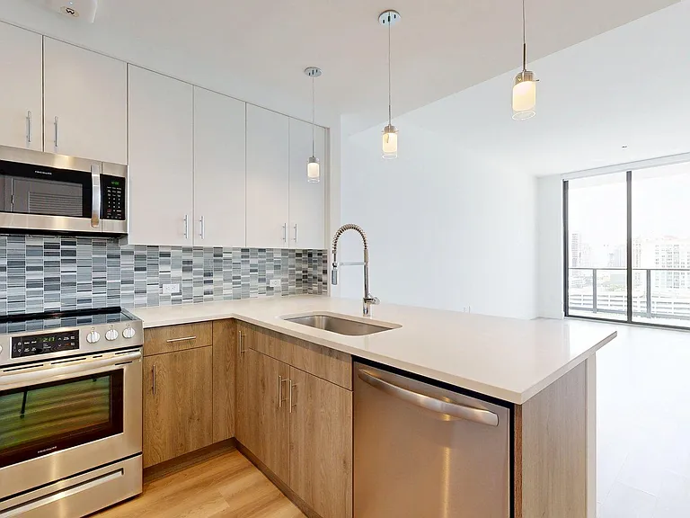Apartment Kitchen with Stainless Steel Appliances, Dining and Living Room with Wood-Style Flooring.