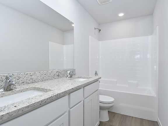 The master bathroom has a dual sink vanity and a tub shower combo.