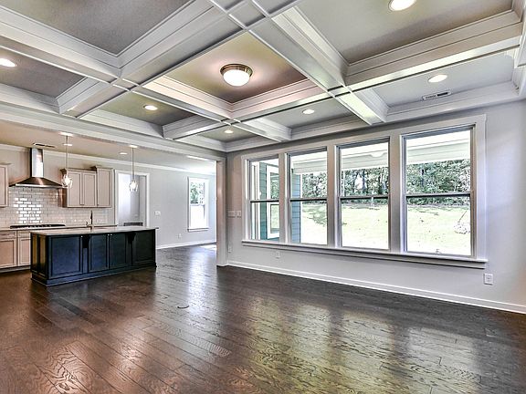 Spacious great room with wall of widows, coffered ceiling, gas fireplace, wood floors and recessed l